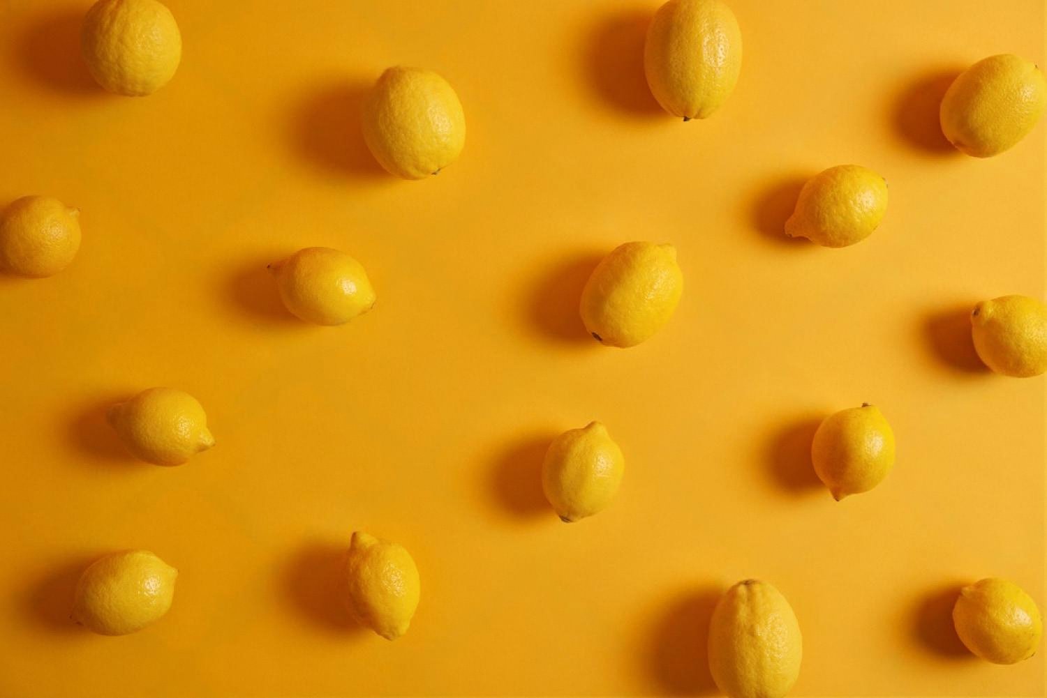 Fresh yellow lemons on an orange background illustrating citrus notes in e-liquid